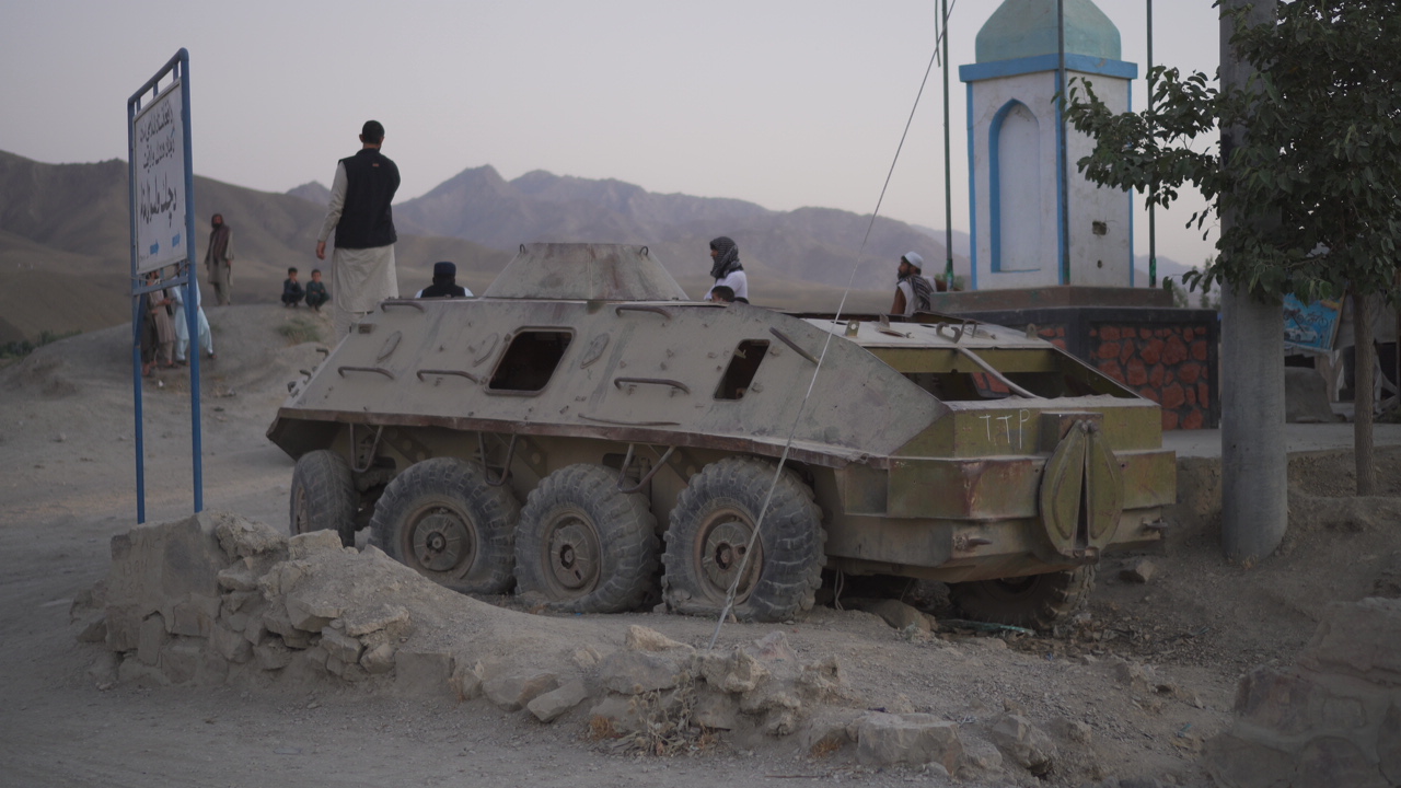 An armoured vehicle beside a blue monument and mountains in Afghanistan